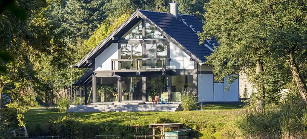 Bild eines modernen Fachwerkhauses vor einem Wald am See
